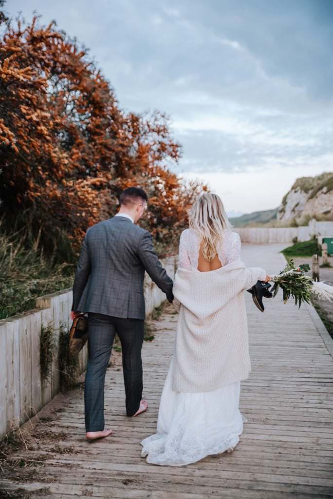 Wedding, bride, and groom walking at the beach . Wedding photographer london